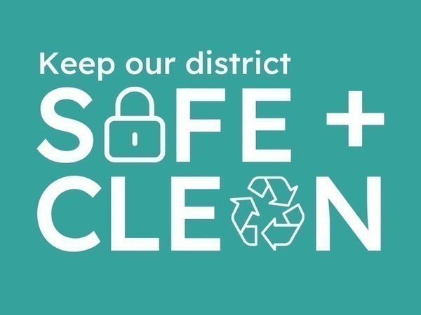 An image with a teal background and white text that reads, "Keep our district SAFE + CLEAN." The 'A' in "SAFE" is replaced by a padlock icon, and the 'A' in "CLEAN" is replaced by a recycling symbol.